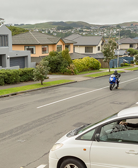 Bike riding straight with car on side street to the left