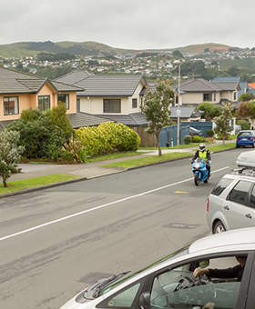 Motorcyclist riding through a T intersection with a car on a left road